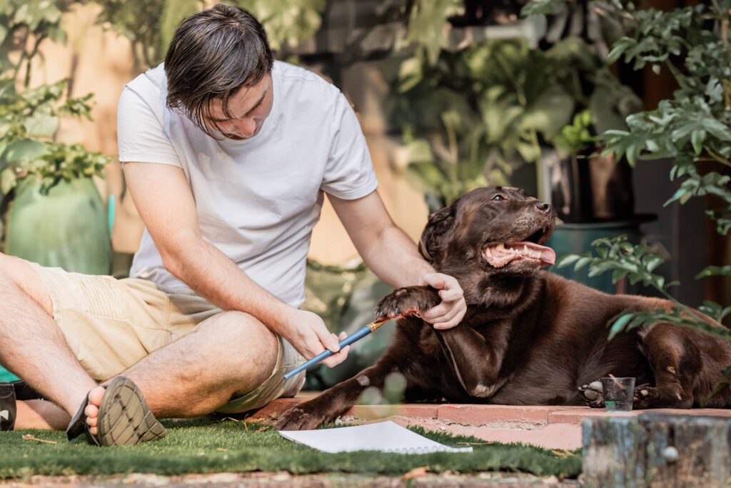 Teenage boy with his pet dog. Painting paw print keepsake during end of life pet photography session before saying goodbye to pet.